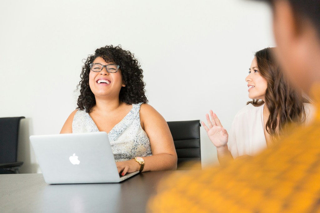 Colleague laughing at her laptop during a meeting
