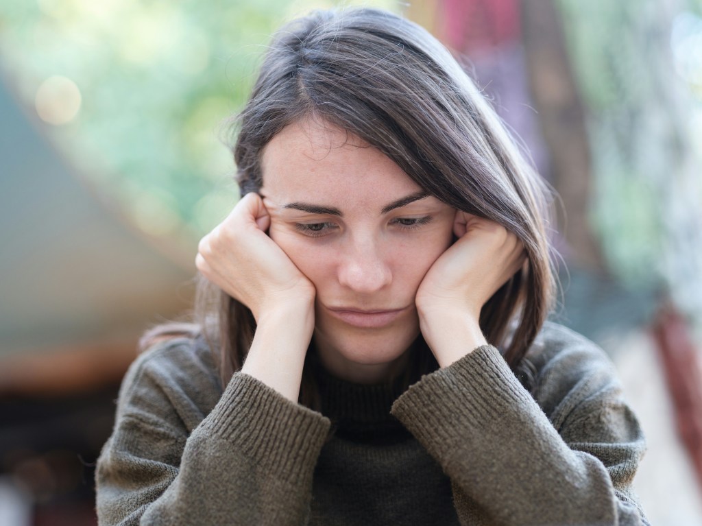 Woman resting her head in her hands, looking down with a worried expression