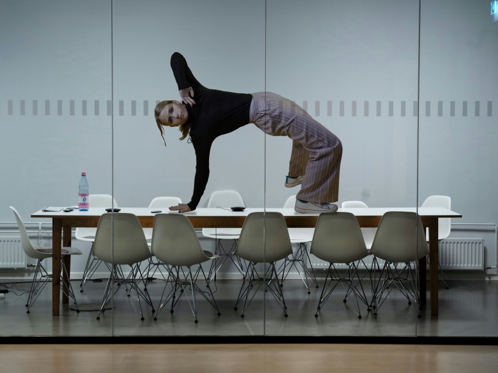 Person bending backward into a bridge pose on top of a conference room table